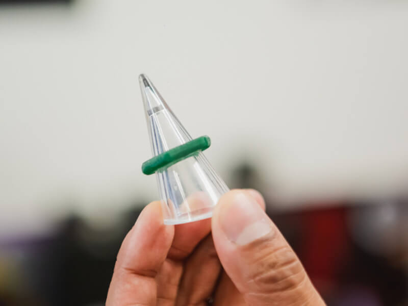 Close up of a green wax casting of a ring on a clear plastic jewellery sizing tool